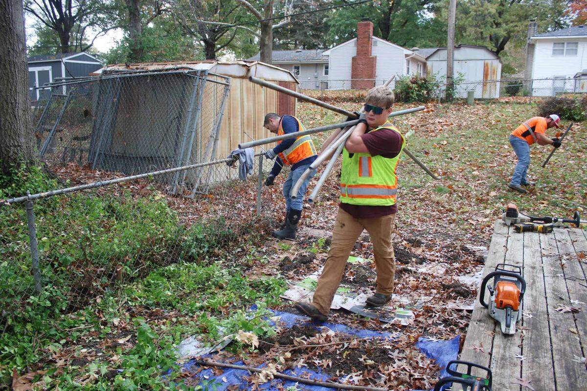 Jordon Williams carries away some damaged fence poles while volunteering for Neighbors Helping Neighbors.