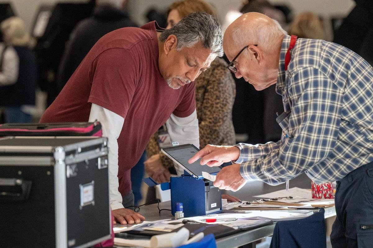 An election supervisor, right, assisted a Johnson County resident who arrived for the first day of in-person advance voting for the 2024 General Election at The Arts and Heritage Center on Saturday, October 19, 2024, in Overland Park.