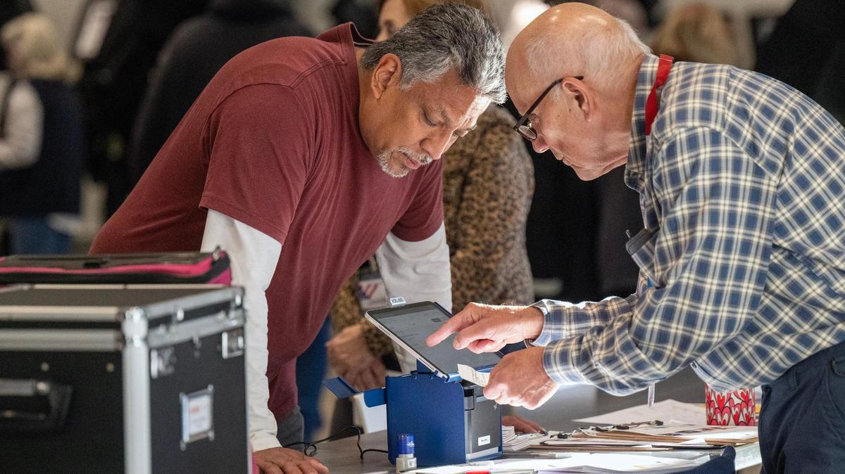 An election supervisor, right, assisted a Johnson County resident who arrived for the first day of in-person advance voting for the 2024 General Election at The Arts and Heritage Center on Saturday, October 19, 2024, in Overland Park.