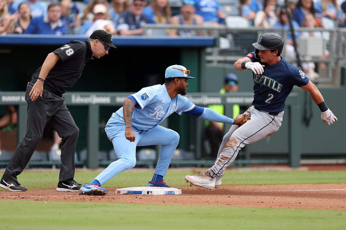 Cole Young #2 of the Seattle Mariners is tagged out while trying to reach third base by Maikel Garcia #11 of the Kansas City Royals during the game at Kauffman Stadium on May 23, 2026 in Kansas City, Missouri.