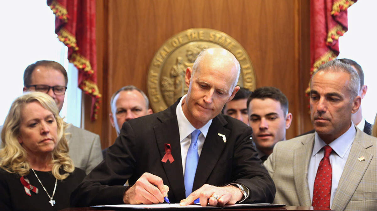 Florida Gov. Rick Scott signed gun and school safety legislation into law on March 9 as family members of those who died in the Marjory Stoneman Douglas High School shooting looked on.