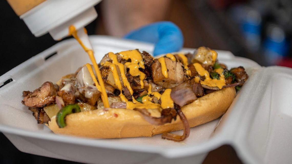 Jesse Goodeyon, owner of Goods by Good, drizzles house-made spicy mayo on top of Goods Hefty Hawaiian Philly sandwich.