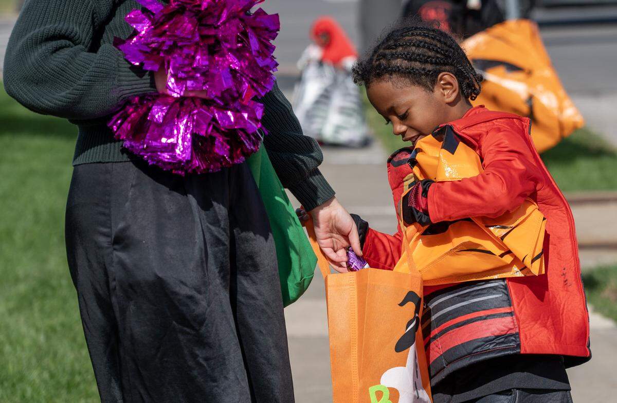 A child in a costume receive candy from a Russell Stover employee during the company's annual Halloween giveaway at the company's headquarters on Friday, Oct. 31, 2025, in Kansas City.