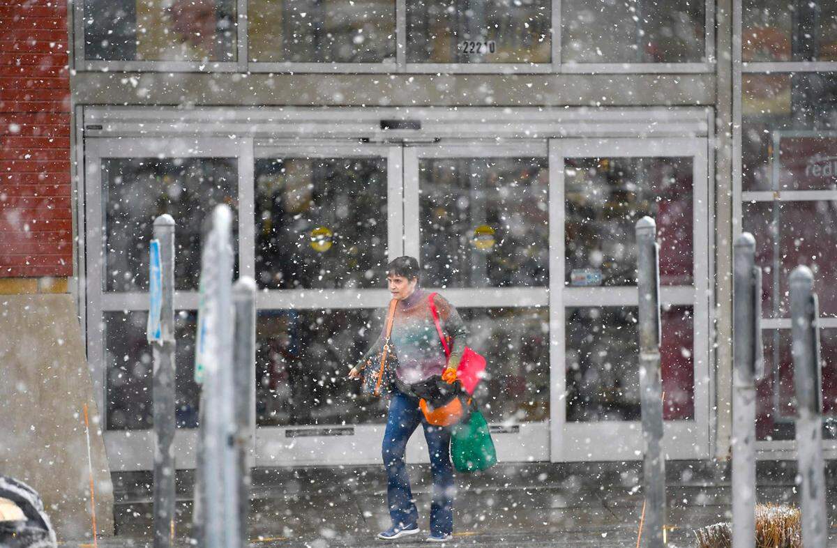 Snow fell as a shopper headed to the parking lot from a discount store on Monday, Jan. 8, 2024, off Shawnee Mission Parkway in Shawnee, Kansas.