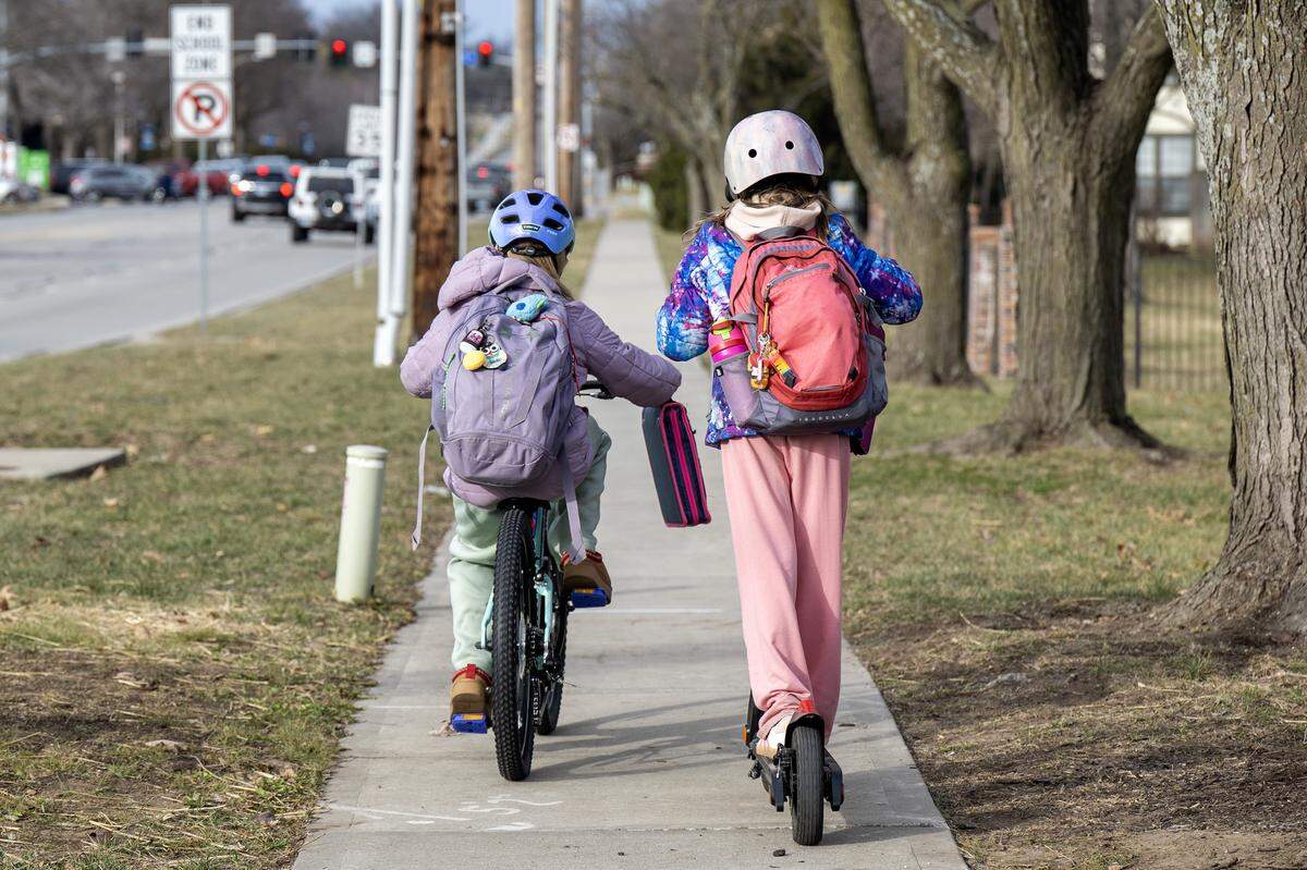 Two children ride a bike and a scooter along Mission Road near Corinth Elementary School on Thursday, Jan. 15, 2026.