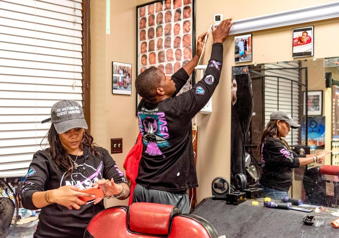 Marie Jackson syncs her phone to paranormal recording devices as her brother Norman Evans installs one of three cameras.