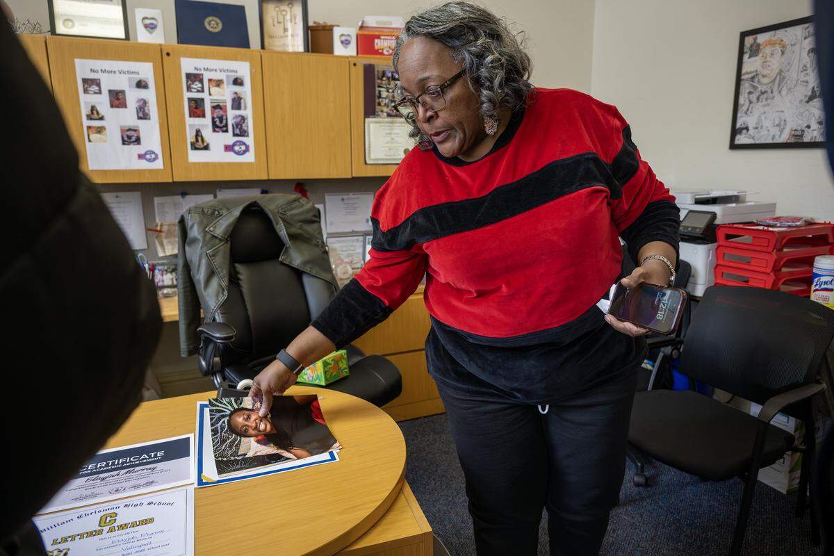Jearl Collins reaches for a photo of Elayjah Murray from a desk during a press conference at KC Mothers in Charge inside the Mohart Building on Wednesday, Dec. 3, 2025, in Kansas City.