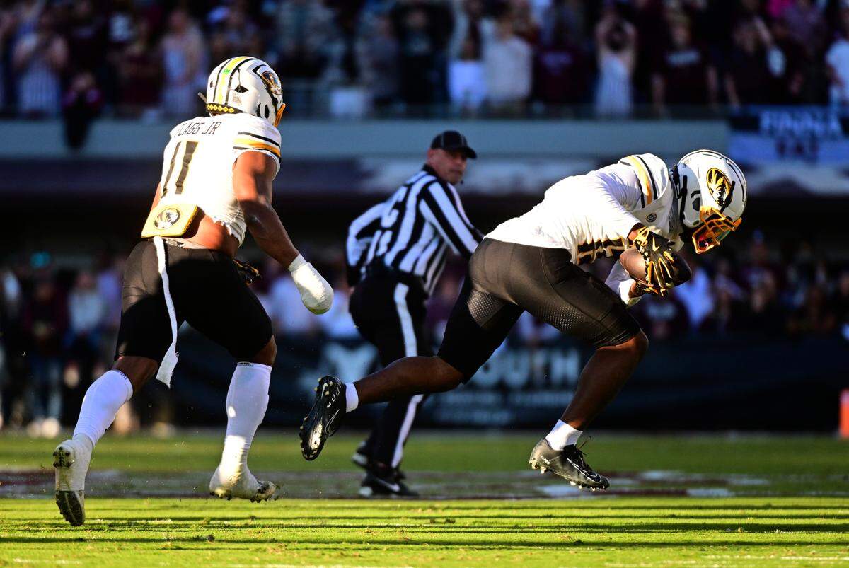Missouri Tigers safety Daylan Carnell, right, recovers a fumble and returns it 68 yards for a touchdown against the Mississippi State Bulldogs during an SEC college football game at Davis Wade Stadium at Scott Field on Saturday, Nov. 23, 2024 in Starkville, Mississippi.