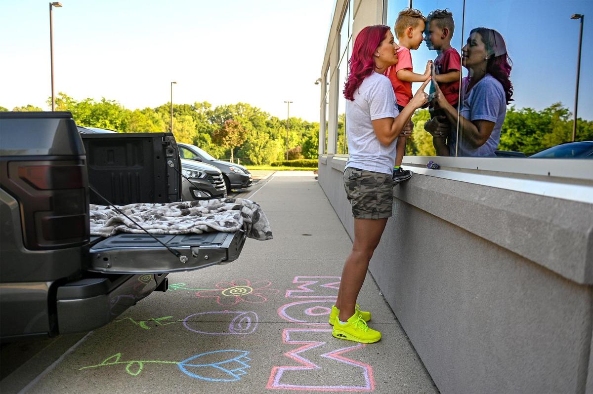Outside of Kindred Hospital Northland, April Shaver of Kansas City holds her 2-year-old son, Malakai, up to the window to see her mother, Gwen Starkey, a COVID-19 patient who has spent more than 100 days on a ventilator.