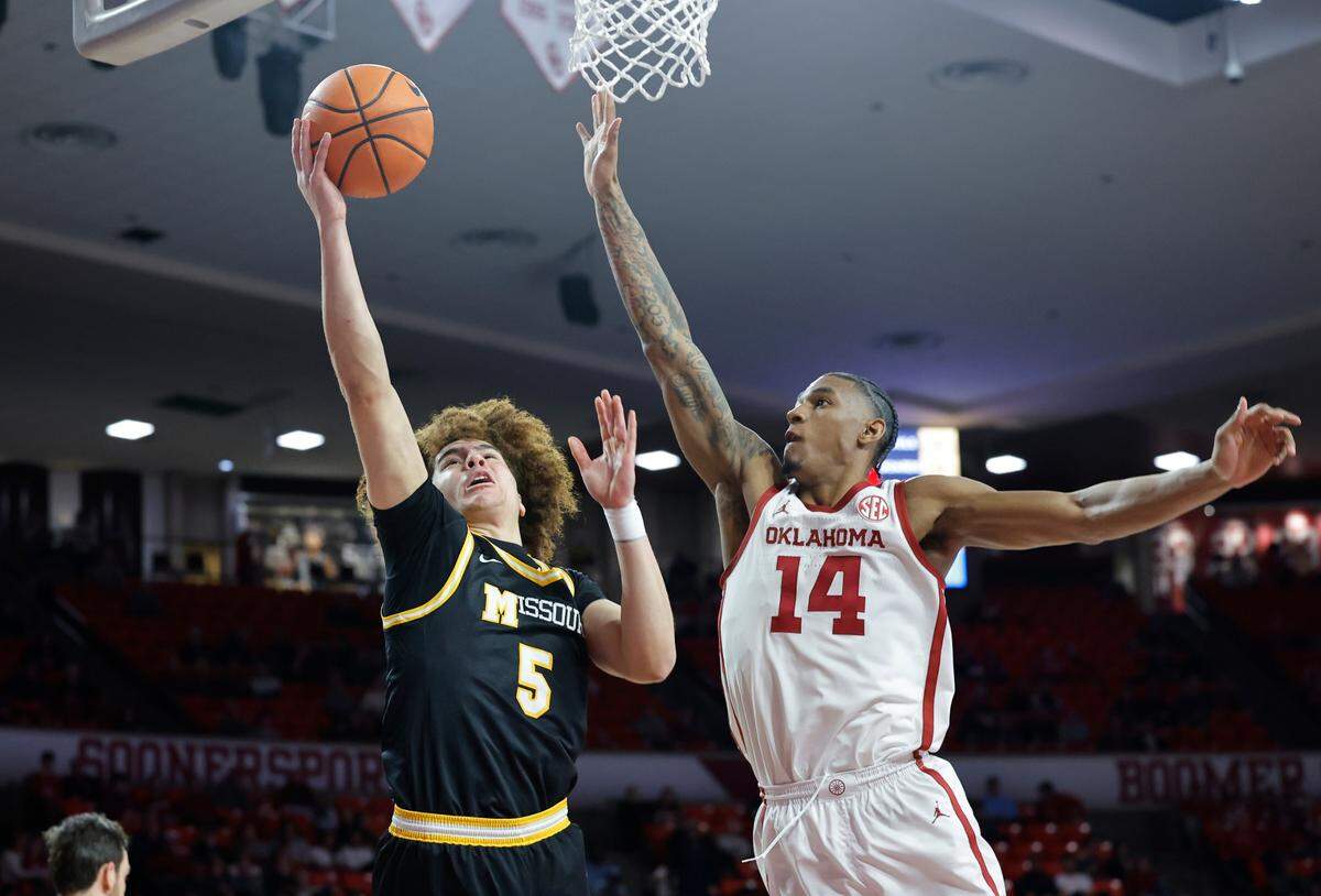 Missouri Tigers guard T.O. Barrett, left, puts up a shot past Oklahoma Sooners forward Jalon Moore during an SEC men’s basketball game at the Lloyd Noble Center on Wednesday, March 5, 2025 in Norman, Okla.