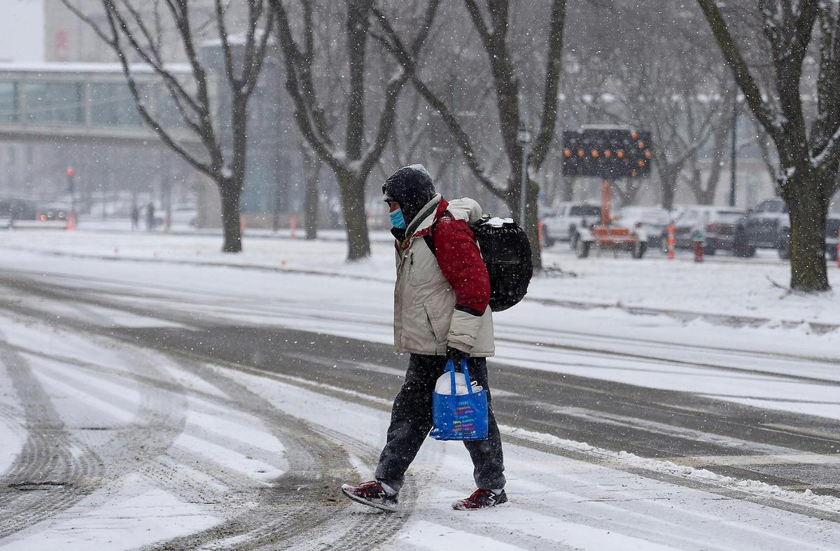 A pedestrian crosses West Pershing Road during a snow storm on Saturday, Feb. 6, 2021. The storm brought with it arctic air that will stick around the Kansas City area for the next several days.