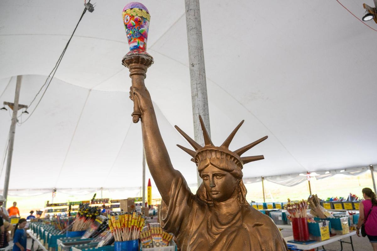 A replica Statue of Liberty holds a fountain firework instead of a torch at Red X Fireworks in Riverside on Thursday, July 3, 2025. The day before Independence Day is traditionally the busiest day of the year for fireworks stands like this.