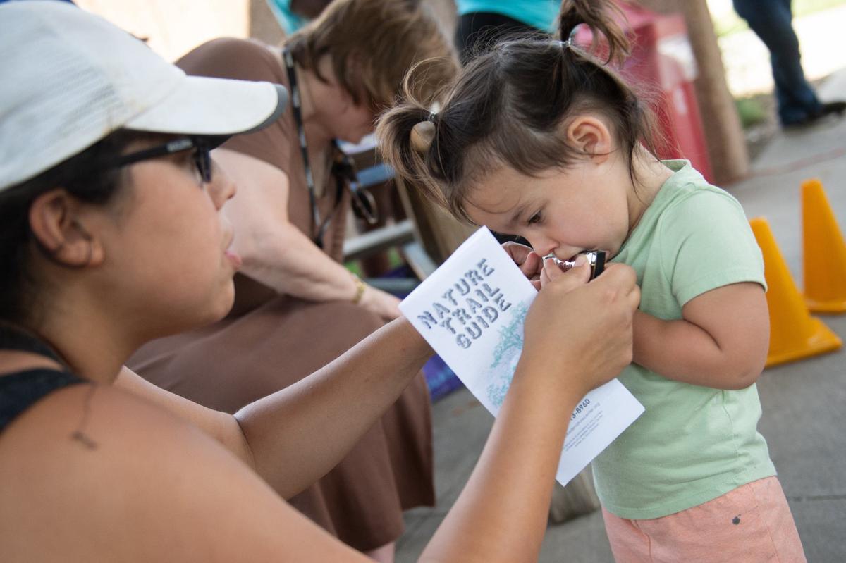Jaclyn Erickson holds a harmonica for her daughter at a beginners workshop during Make Music Day.
