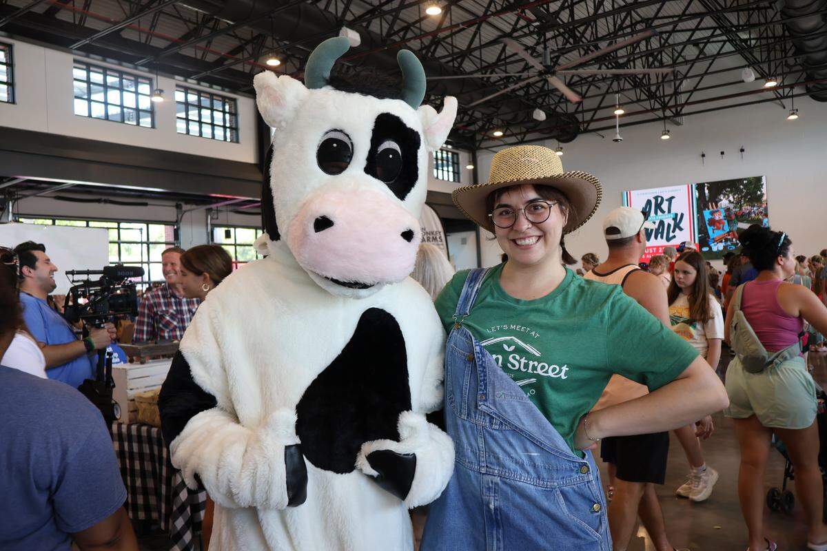 A mascot and a worker pose in the indoor pavilion.
