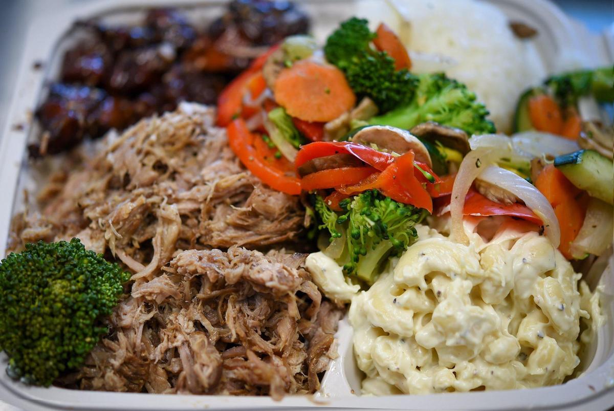 A mixed plate lunch featuring Luau Pig and Honolulu Chicken with macaroni salad and seasoned vegetables at the Hawaiian Bros Island Grill at 8805 State Line Road.