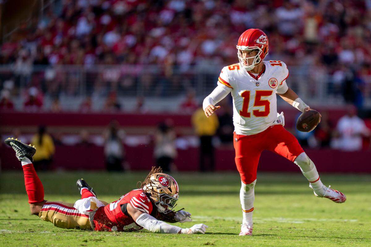 Kansas City Chiefs quarterback Patrick Mahomes (15) runs past San Francisco 49ers linebacker Fred Warner (54) during the third quarter at Levi’s Stadium.