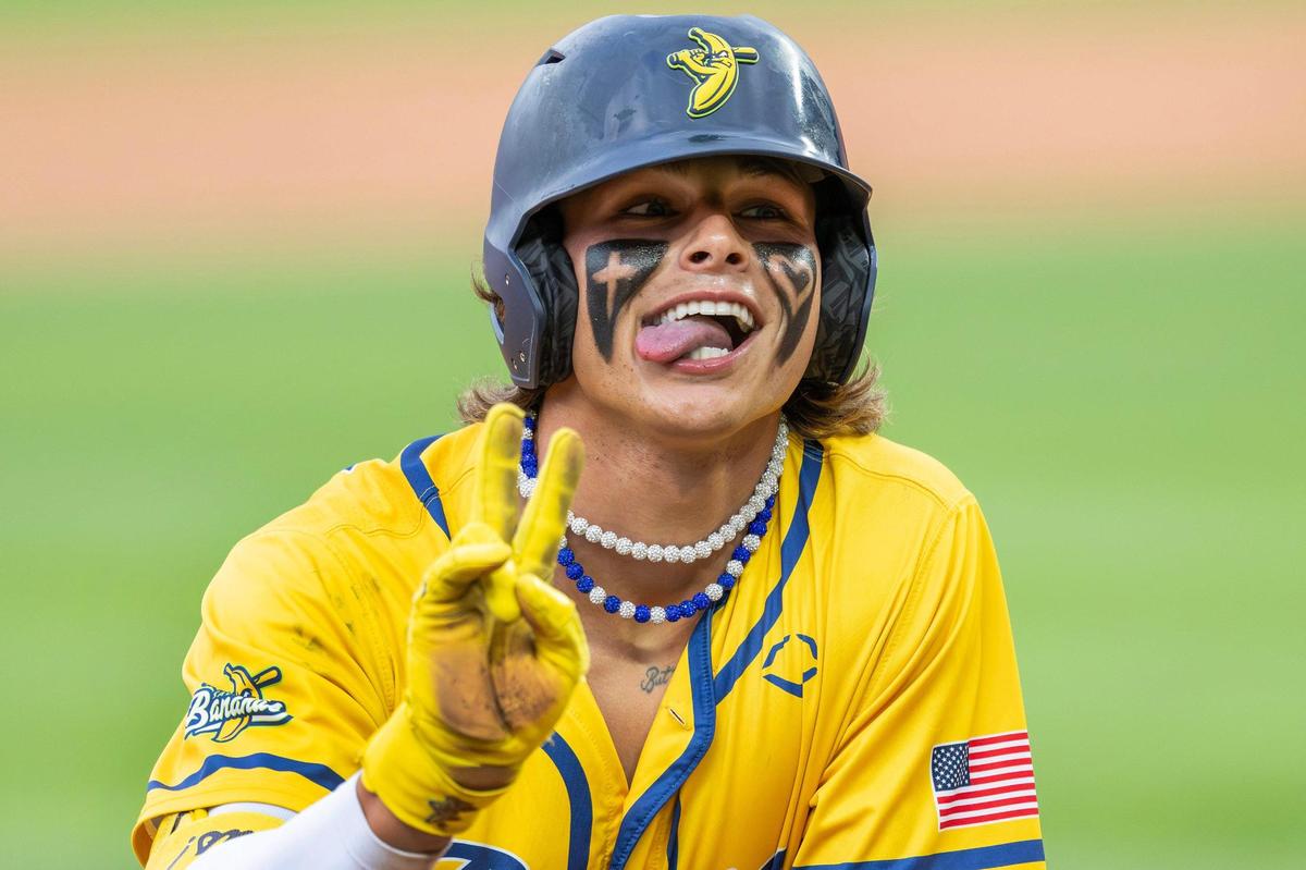 Savannah Bananas utility player KJ Jackson (4) flashes a peace sign and sticks out his tongue while sliding into third base during the second inning of a Banana Ball game against the Firefighters at Kauffman Stadium on Friday, May 23, 2025, in Kansas City.