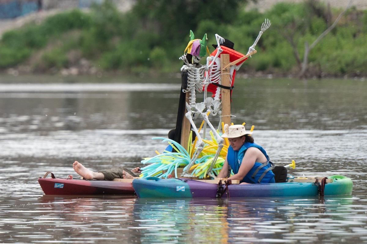 Two Kawsmouth River Carnival boat parade participants steer kayaks decorated with skeletons away from Kaw Point.
