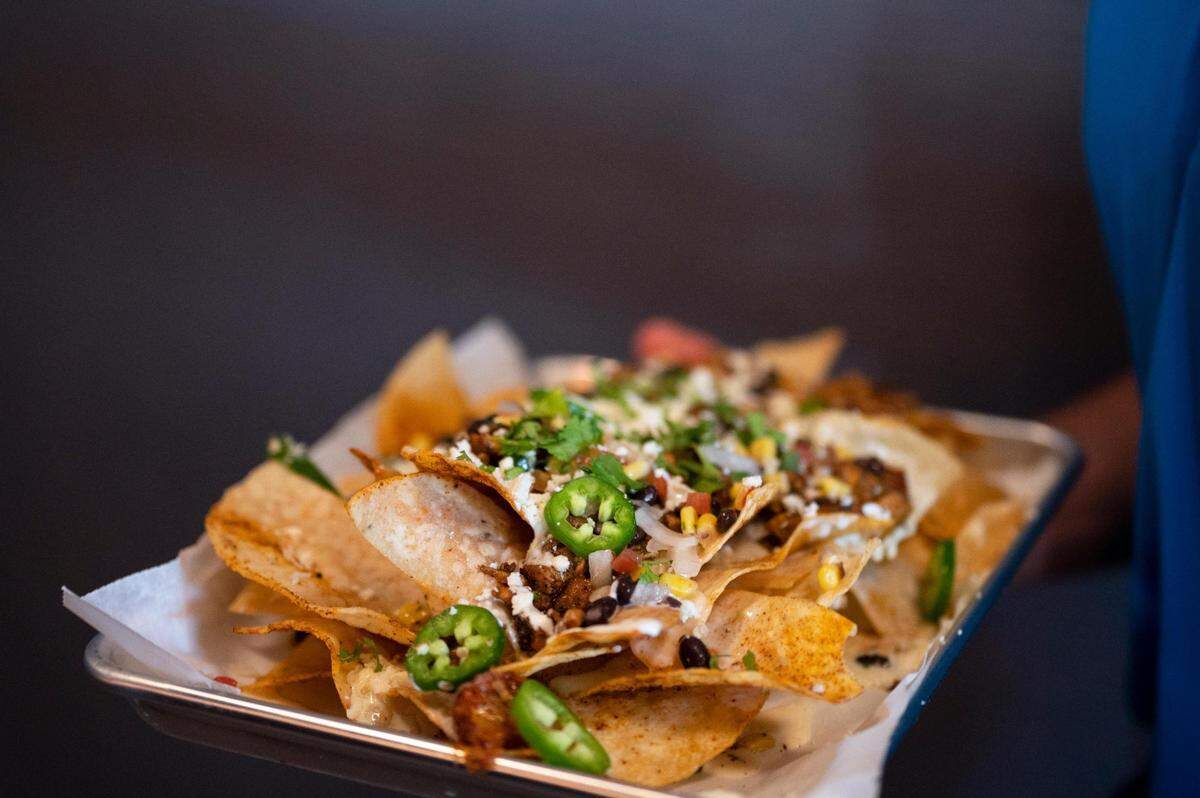 Chicken nachos are carried out at a preopening event at Briarcliff Barrio.