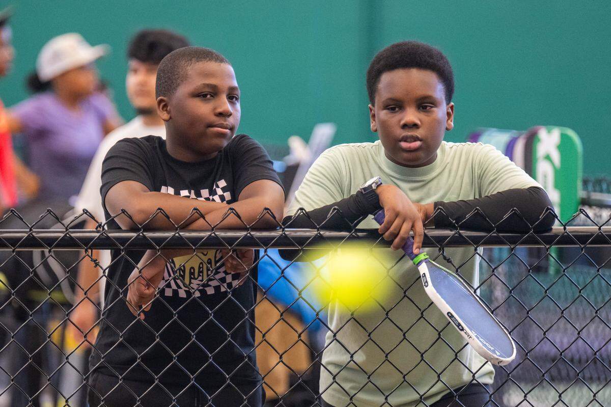 Ayden Campbell, 11, and Ben Bestey, 12, watch a rally during a meeting of the Black Pickleball Club at SW19 at the Stadium, on Sunday, February 22, 2026, in Kansas City. The club, started by Brandan Jackson, hosts weekly meetups every Sunday as a space for Black people to participate in pickleball.