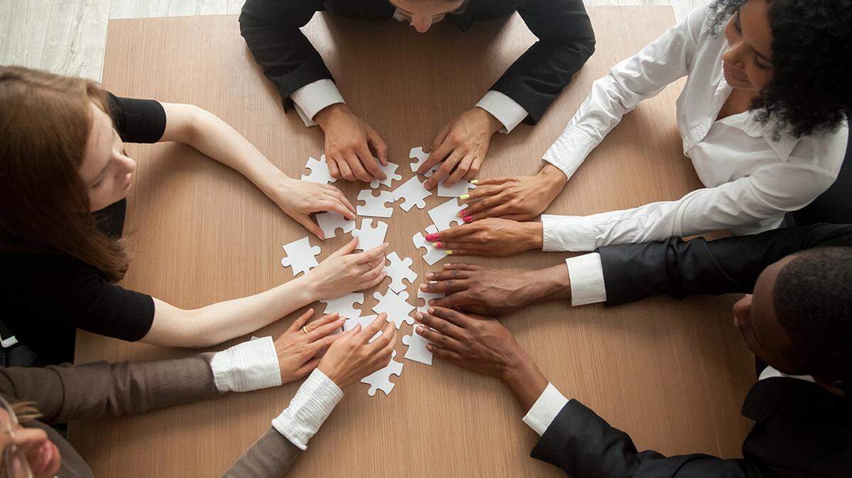 Diverse team people assembling jigsaw puzzle, multiracial group of black and white colleagues engaging in successful teamwork finding business solution, corporate unity teambuilding concept, top view diversity equity inclusion dei racial race cooperation