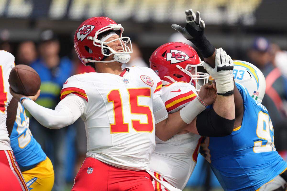 Kansas City Chiefs quarterback Patrick Mahomes (15) throws the ball under pressure from Los Angeles Chargers defensive tackle Otito Ogbonnia (93) in the first quarter at SoFi Stadium.