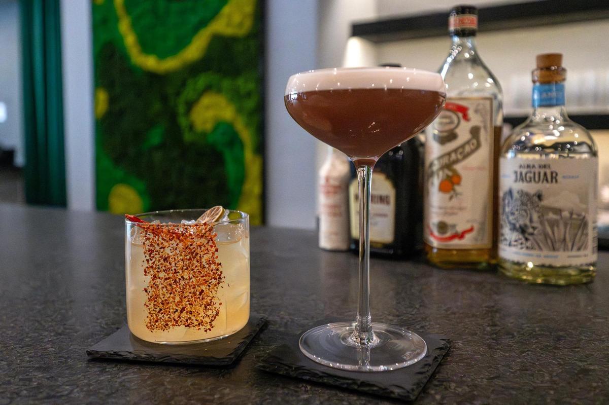 The house margarita and Cherry Eclipse cocktails are pictured at Kohinoor, a cocktail bar and lounge. The margarita is topped with a dried lime slice and chili, finished with house made chili seasoning, while the Cherry Eclipse features blanco tequila, cherry liqueur, and mint-coriander syrup.