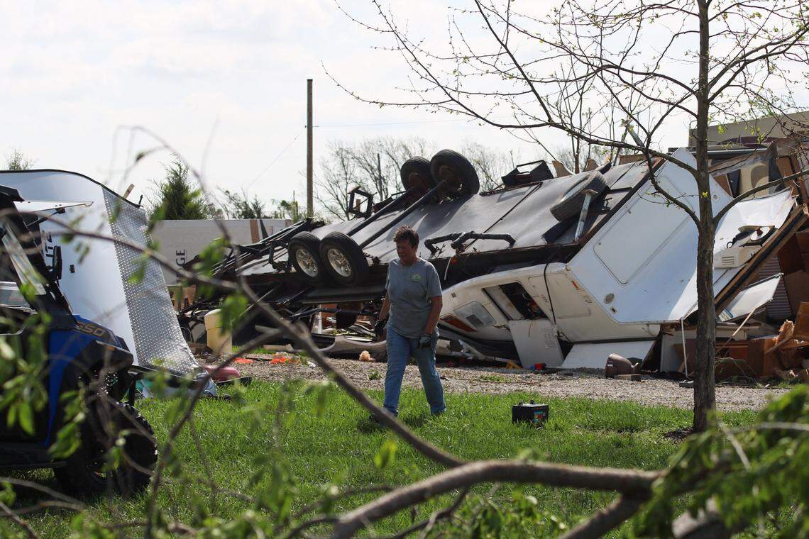 A woman helps clean up downed limbs and items from RVs wrecked by a tornado in Hillsdale, Kansas.