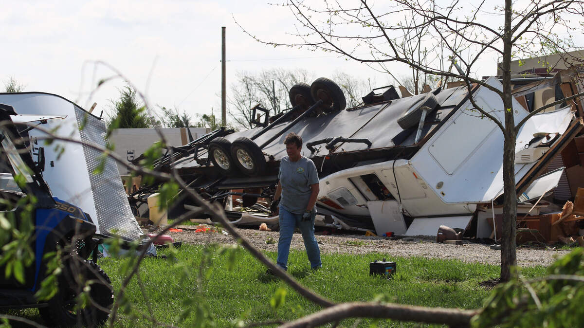 A woman helps clean up downed limbs and items from RVs wrecked by a tornado in Hillsdale, Kansas.
