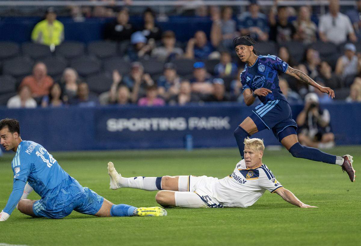 LA Galaxy defender Jakob Glesnes (5) looks on Sporting Kansas City forward Calvin Harris (11) reacts as his kick scored a goal against LA Galaxy goalkeeper James Marcinkowski (12) in the second half at Sporting Park on Wednesday, May 13, 2026, 2026, in Kansas City, Kansas. Sporting KC defeated the LA Galaxy, 3-1.