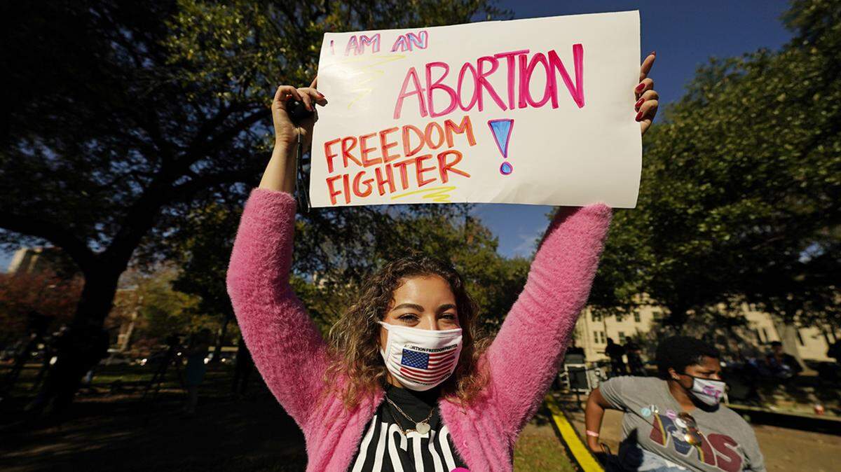 An abortion rights supporter holds one of many signs that were displayed at a reproductive rights rally at Smith Park in Jackson, Mississippi, Wednesday, Dec. 1, 2021.