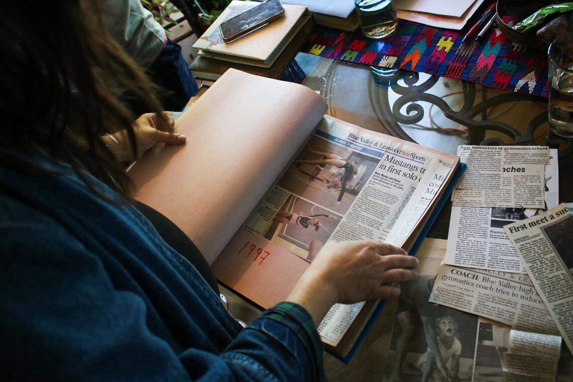 Lisa Rodriguez flips through a scrapbook of newspaper clippings at her father Keno Rodriguez’ house on April 19, 2026. Keno, who died on April 6, 2026, was influential in the KC gymnastics community for starting youth programs at Blue Valley Recreation. He also coached high school gymnastics in the Blue Valley district in the 1990s.