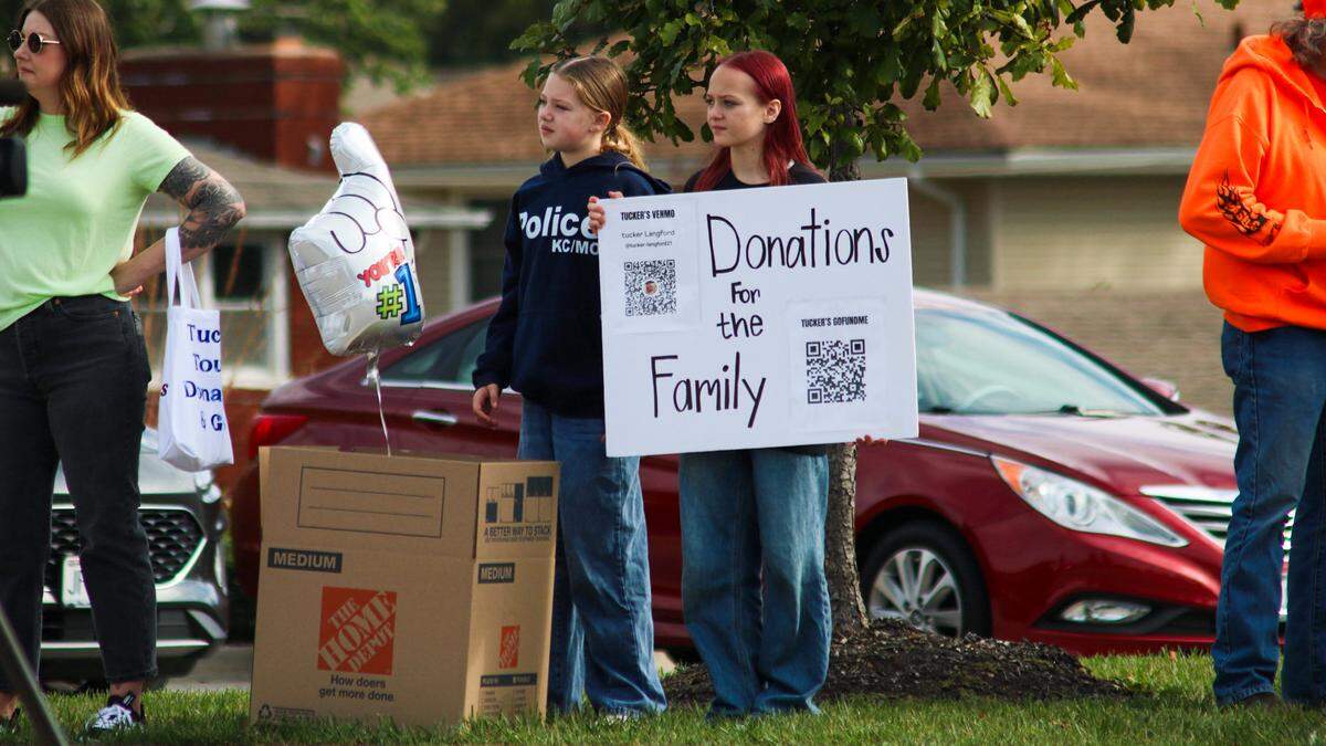 People hold signs for donations during a parade for Tucker Langford, a 3-year-old battling terminal illness, on Saturday, Oct. 11, 2025.