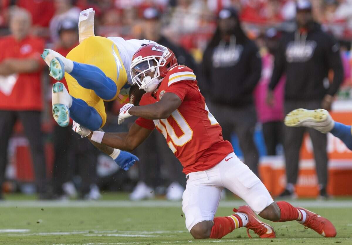 Kansas City Chiefs cornerback Nohl Williams (20) upends Los Angeles Chargers running back Omarion Hampton (8) during the first half on Sunday at Arrowhead Stadium.