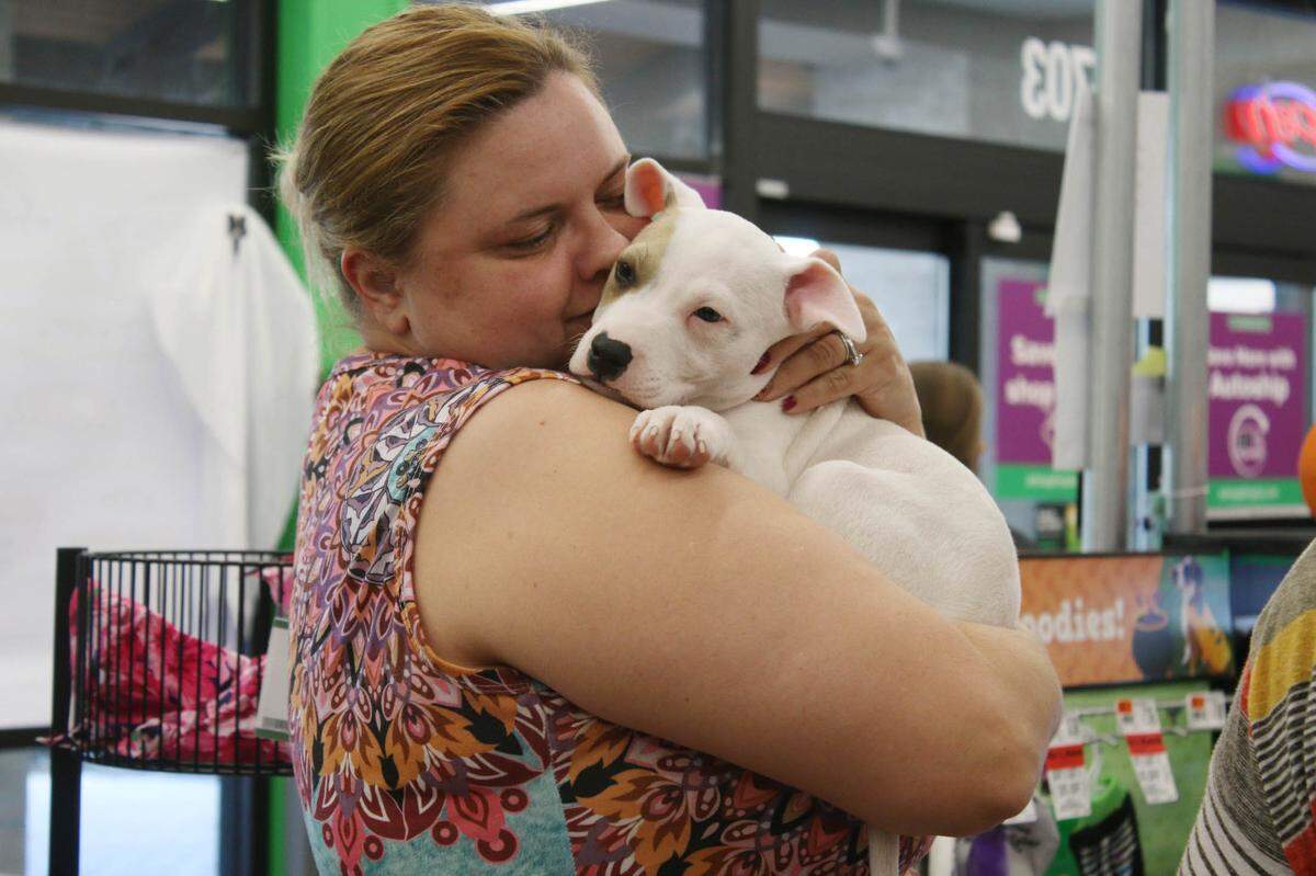 Tasha Hamilton of Raymore gives Beans a hug at a Pawsitive Tails event at Pet Supplies Plus in Leawood.