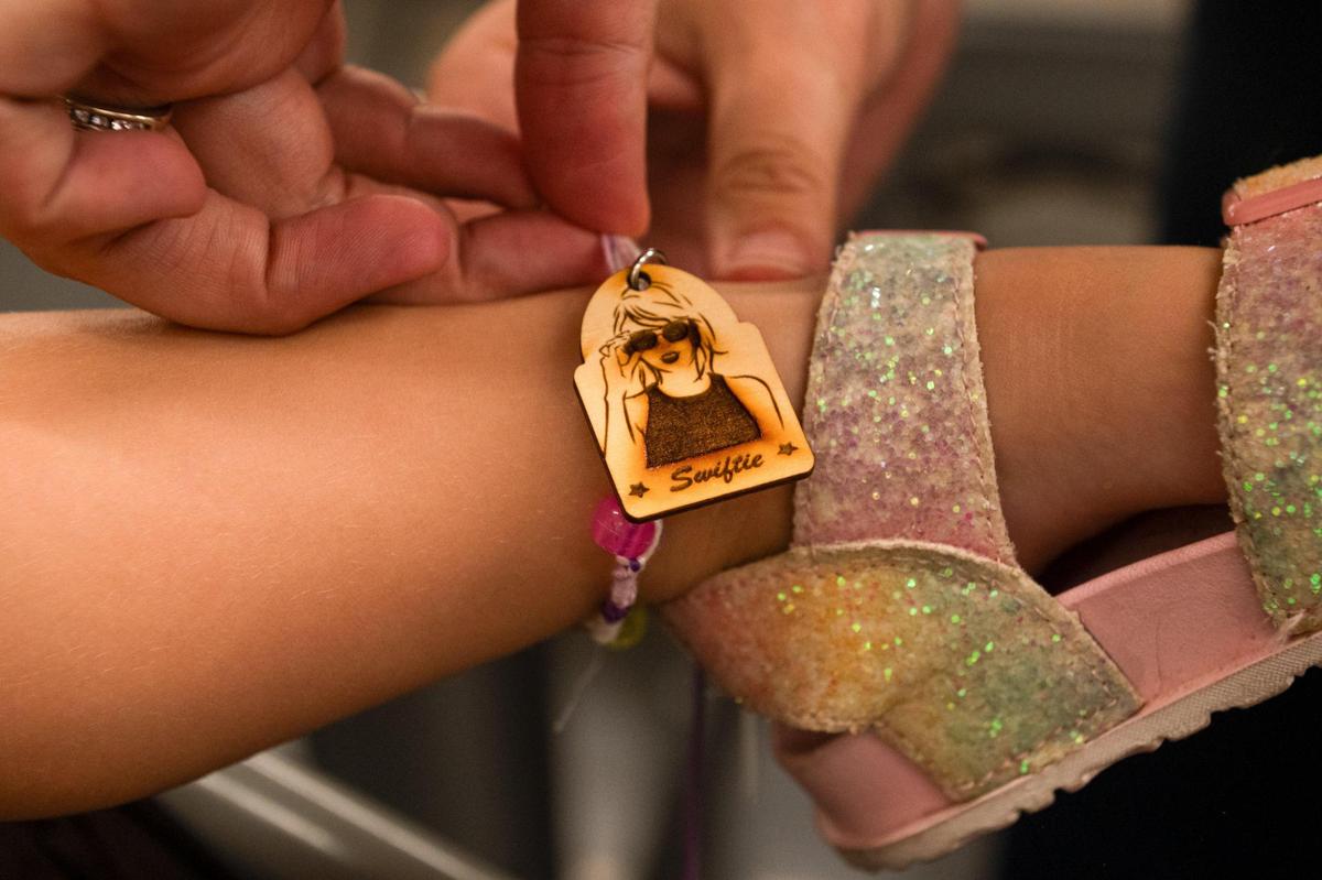Laura Julien ties a Taylor Swift friendship onto her daughter Wynter Julien’s ankle inside of the Makers Studio at Science City on Wednesday, July 5, 2023, in Kansas City. The friendship bracelets comes equipped with a laser printer wooden charm of Taylor Swift.