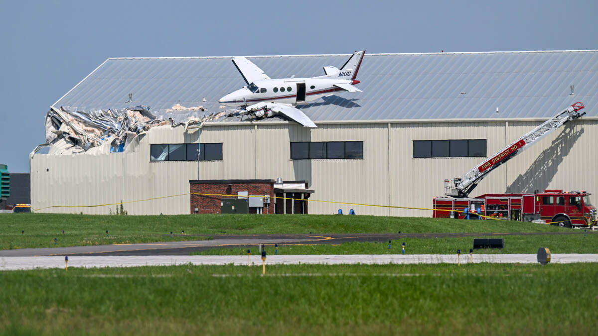 A Beechcraft airplane rests on the roof of a building at New Century AirCenter after it made a crash landing that left it on the roof on Monday, June 16, 2025.