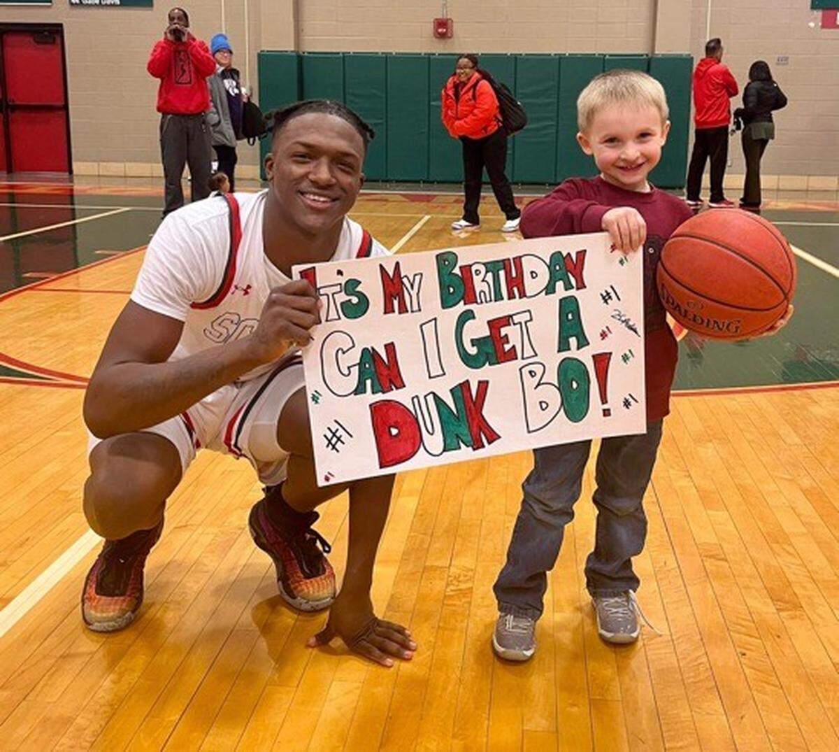 Ketraleus ‘Bo’ Aldridge smiles after a high school game with a fan holding a sign.