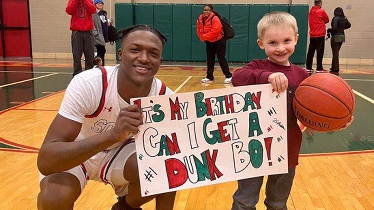 Ketraleus “Bo” Aldridge, left, smiles with a young sign-holding fan after a basketball game in Topeka.