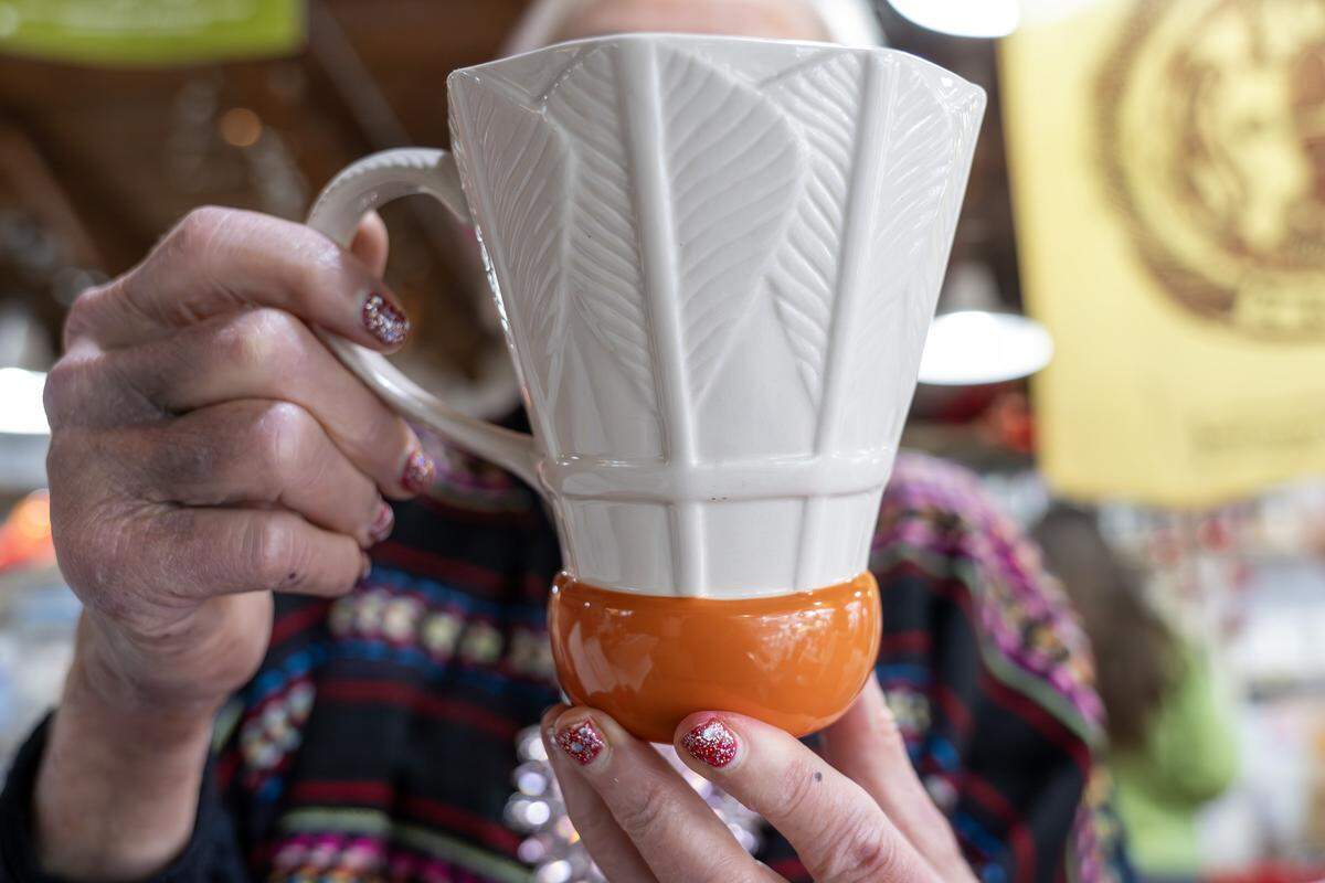 Irma Starr shows a shuttlecock-themed mug she created for the Nelson-Atkins Museum of Art while giving a tour of her home studio on Thursday, Dec. 11, 2025, in Kansas City.