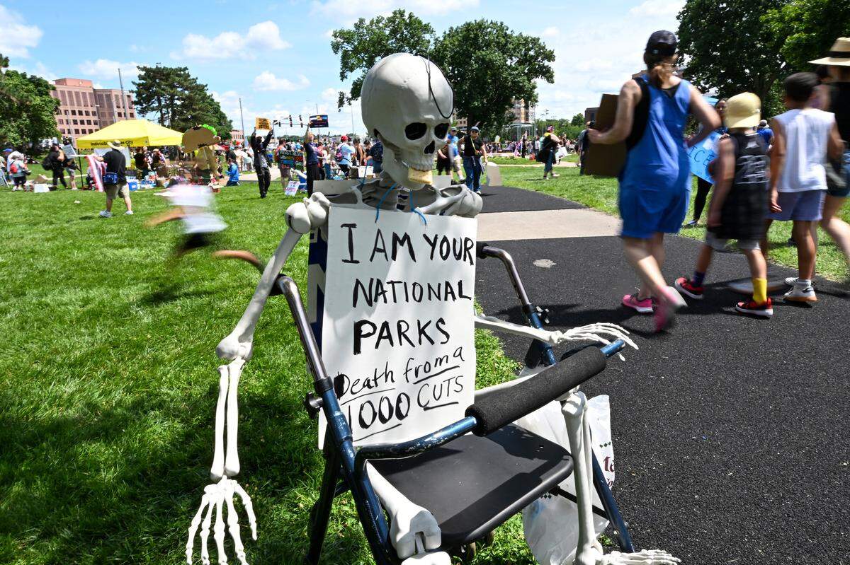 A plastic skeleton with a message about cuts to the National Parks system by the Trump administration was on display during the “No Kings” rally Saturday, June 14, 2025, at Mill Creek Park in Kansas City.