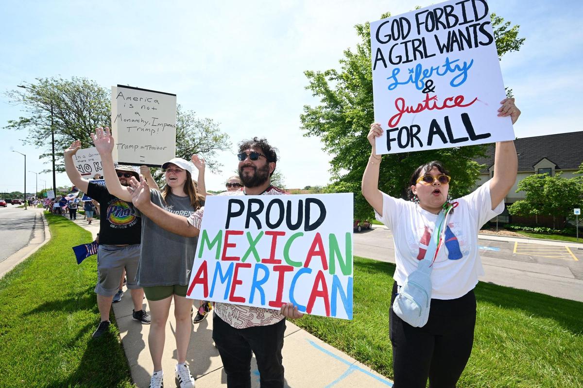 Yadin Amador, center, and Juli Casas, right, both of Gardner, were in Lenexa on Saturday, June 14, 2025, for the “No Kings” rally. Several “No Kings” rallies intended to protests the policies of the Trump administration are scheduled across the country and the Kansas City metro area.