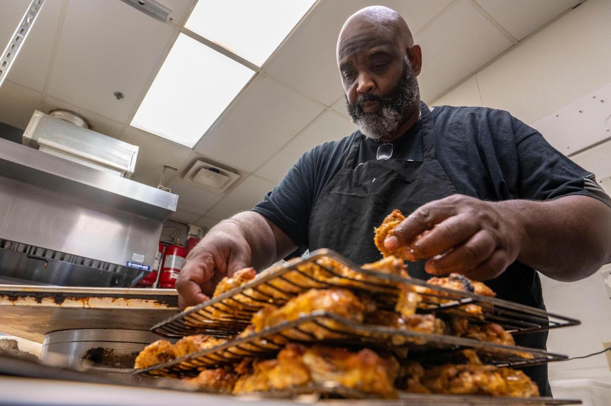 Lutfi Khalifa arranges seasoned chicken on racks to put inside a smoker at his Lutfi’s Fried Fish restaurant in Lee’s Summit.