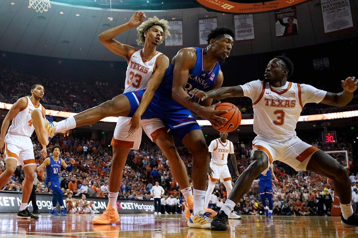 Texas forward Tre Mitchell, center, fights for a rebound with Texas forward Tre Mitchell, left, and guard Courtney Ramey, right, during the first half of an NCAA college basketball game, Monday, Feb. 7, 2022, in Austin, Texas. (AP Photo/Eric Gay)
