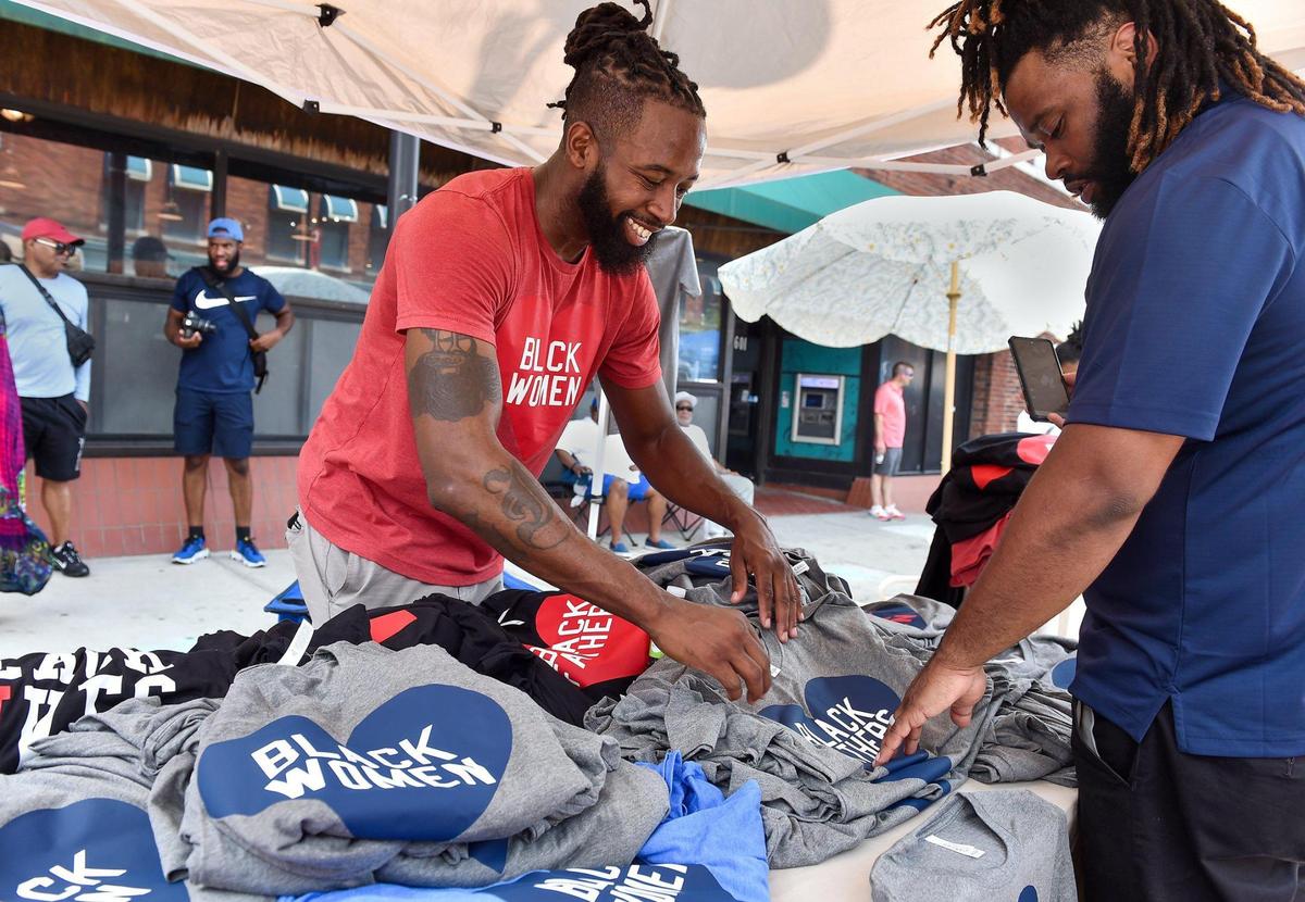 Jeff Harris with Heart Black Lives, shows customer Cameron Gentry of Kansas City some of the t-shirts for sale at Kansas City’s Juneteenth Heritage Festival in the 18th and Vine Jazz District Saturday, June 19, 2021. Gentry purchased two t-shirts that say Black Fathers.