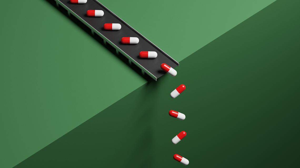 Conveyor belt with red and white pills on a green background dropping the pills over an edge, the image can illustrate conceptual ideas around Pharmaceutical industry, big pharma, Pharmaceutical business and production and manufacturing of Pharmaceutical products like medicine and opioids