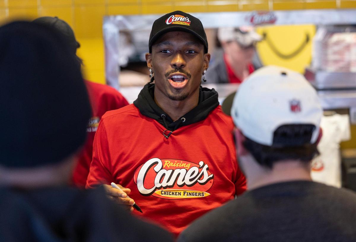 Kansas City Chiefs receiver Mecole Hardman Jr. talks to customers while working the counter at a Raising Cane’s restaurant in Blue Springs on Tuesday. Hardman was joined by teammate L’Jarius Sneed at the event.