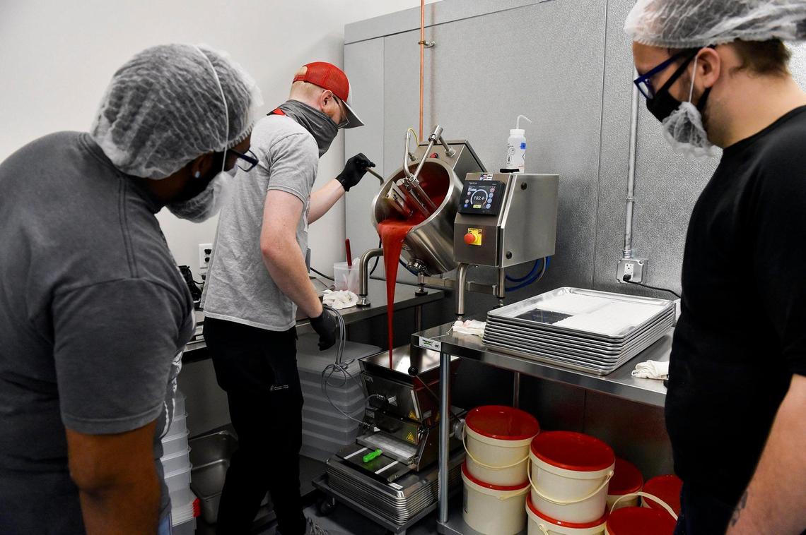 Clovr “gummie techs” Toussaint Tindal, left, and Will Finley, right, watched as Zach Romey, founder of Robhots brand gummies, showed them how to produce Robhots.