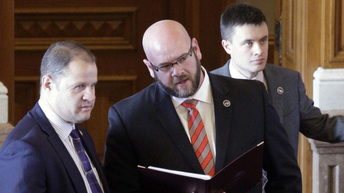 Kansas state Rep. Stephen Owens, R-Hesston, center, confers with B.J. Harden, left, chief of staff to House Majority Leader Dan Hawkins, R-Wichita. Owens is championing the creation of a new financial institution in Kansas.