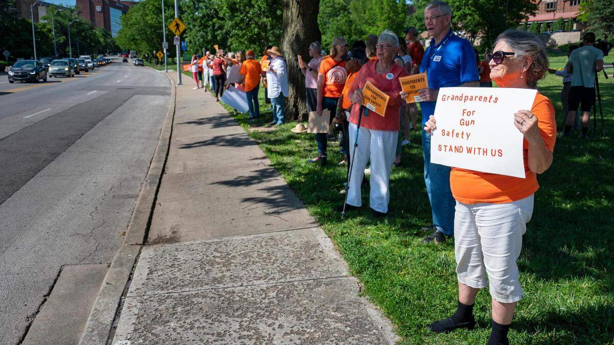 Barb Darter, a member of Grandparents for Gun Safety, holds a sign for passing motorists to see as people gather at the Plaza Fountain at Mill Creek Park on Friday, for a peaceful demonstration focusing on the epidemic of gun violence across the United States. The event is part of National “Wear Orange” weekend, which is dedicated to the people who have been affected by gun violence.